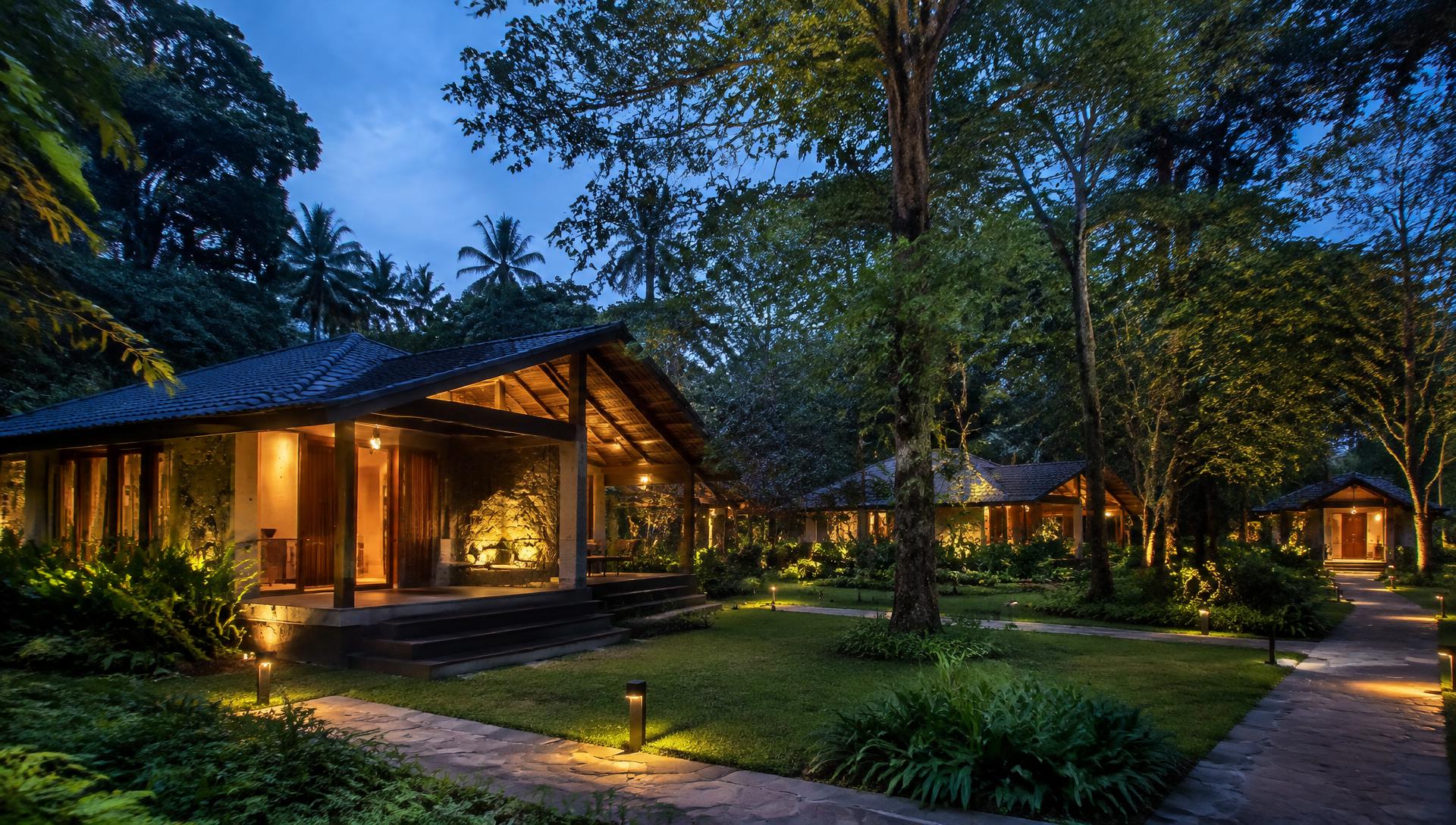 Resort cottages lit at dusk among tall forest trees